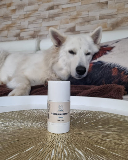 Stick protecteur Cocon NAÏA devant un chien blanc couché sur le canapé